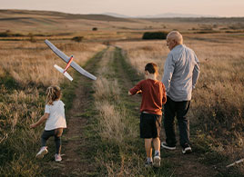 Photo of a grandparent with children throwing toy plane. Link to Life Stage Gift Planner Over Age 65 Situations.