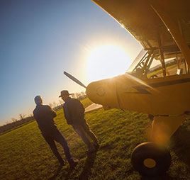 Photo of two people standing in front of plane. Link to Gifts of Life Insurance.